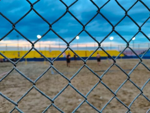 Chain link fence on soccer field and sky background.