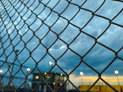 Chain link fence on soccer field and sky background.