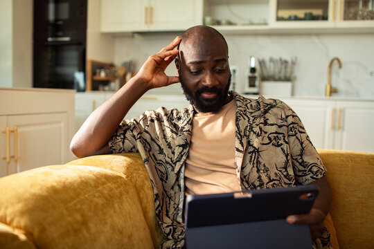 Man relaxing on sofa using a tablet at home