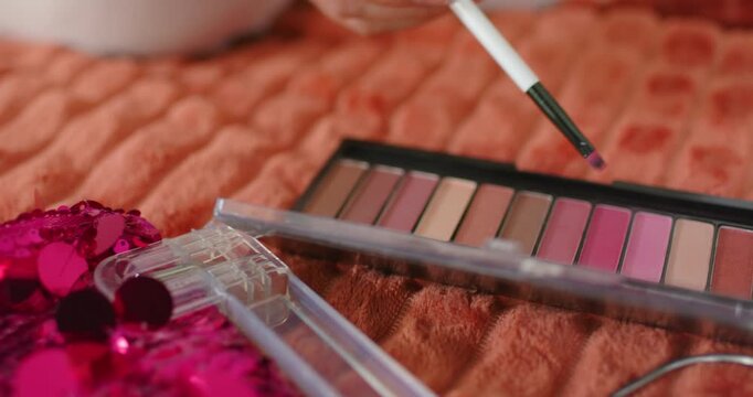 Small brush is entering from top-right, dipping into mid-pink pan to test shade on orange quilt