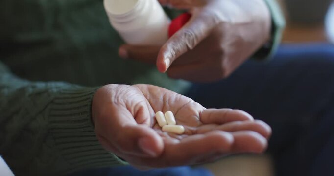 Bottle holder is tipping bottle and pouring capsules into open palm while pointing, preparing dose