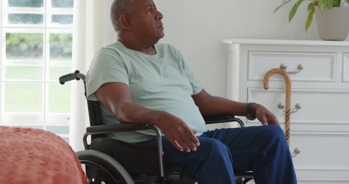 Senior African American man in wheelchair resting Cam pulling back showing bedroom turning to cane