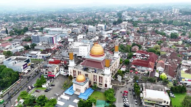 Aerial view of Masjid Agung Kota Sukabumi with its golden dome and minarets surrounded by the dense urban landscape of Sukabumi, West Java, Indonesia.