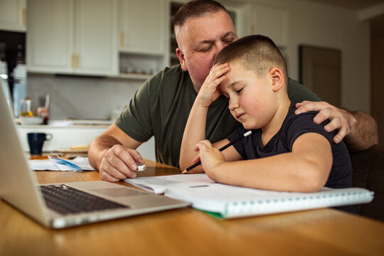 Father comforting son during homework at kitchen table
