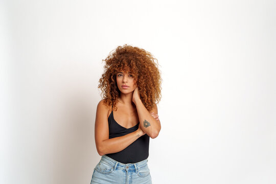 Hispanic woman with curly red hair and tattoo posing, Spain