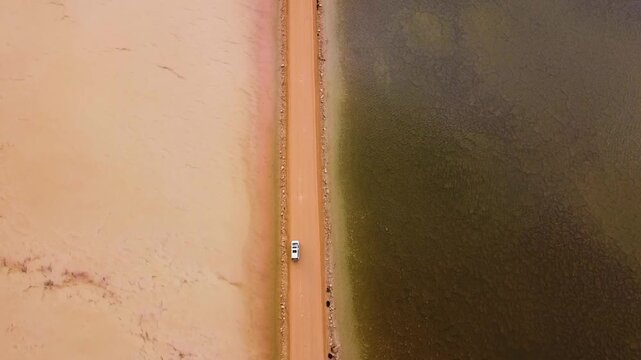 Aerial view of Lake Macdonnell with its vibrant pink and green waters separated by a dirt road in Penong, South Australia, Australia.