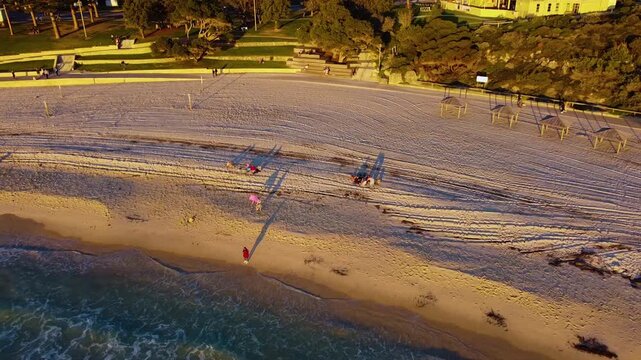Aerial view of Cottesloe Beach with long shadows on the sand during golden hour in Western Australia, Australia.