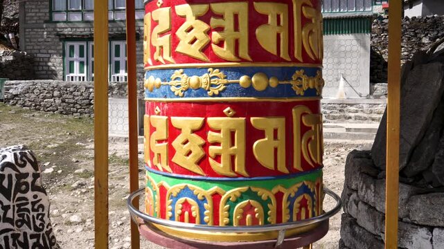Traditional buddhist prayer wheel with mantra om mani padme hum spinning in a nepalese village, representing a spiritual meditation practice for accumulating wisdom and good karma