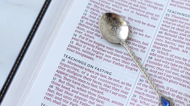 Christian fasting text in open holy bible with a spoon.