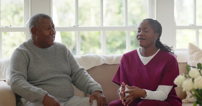 African American caregiver raising right hand while chatting with senior man holding remote on sofa