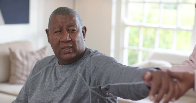 African American woman noticing Senior man reaching, guiding hand for therapy on couch, copy space