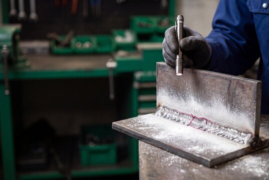 Technician performing dye penetrant testing on a welded metal piece
