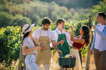 Naklejka premium Friends enjoying drinks and preparing food together among grapevines