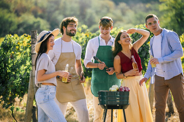Naklejka premium Group of friends enjoying an outdoor meal preparation in a vineyard