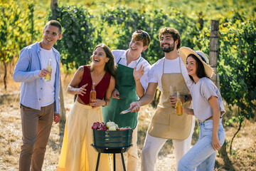 Naklejka premium Cheerful friends gathering around food and drinks in a vineyard