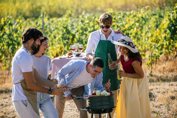 Naklejka premium Friends preparing a meal together around a barbecue in the vineyard