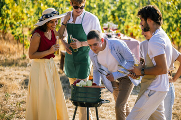 Naklejka premium Friends cooking together around an outdoor grill in a vineyard