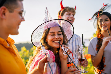 Naklejka premium Woman in witch hat smiling with friends at a Halloween vineyard party