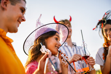 Naklejka premium Friends celebrating Halloween outdoors with a woman in a witch hat