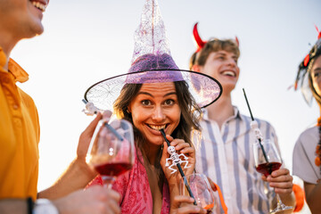 Naklejka premium Smiling woman in a witch hat celebrating Halloween with friends