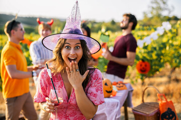 Naklejka premium Surprised woman in witch costume enjoying a Halloween vineyard party