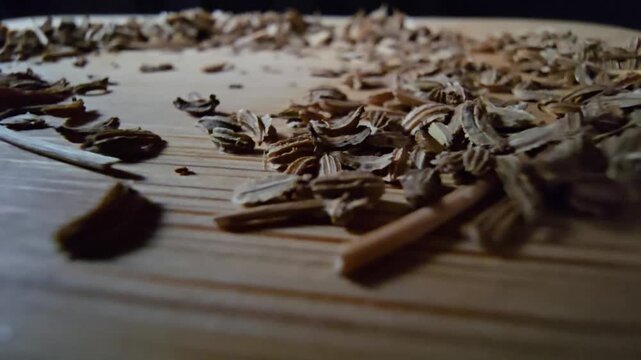 Macro shot of dry carrot seeds spread on a wooden board surface, ideal for agriculture and gardening themes.   