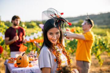 Naklejka premium Smiling woman wearing a Halloween headpiece at an outdoor vineyard party