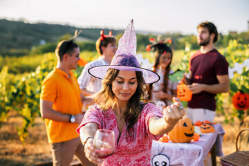 Naklejka premium Woman in witch costume holding a drink during a Halloween vineyard celebration