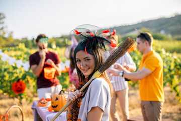 Naklejka premium Woman carrying a decorated broom during a Halloween celebration in a vineyard