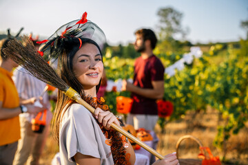 Naklejka premium Woman in Halloween costume posing with a decorated broom among grapevines