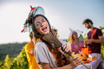 Naklejka premium Woman in Halloween costume carrying a decorated broom during a vineyard party