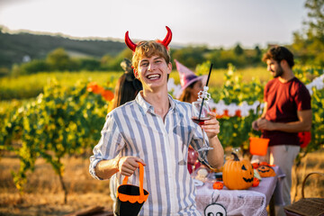 Naklejka premium Man in devil horn costume smiling with a wine glass at a vineyard party