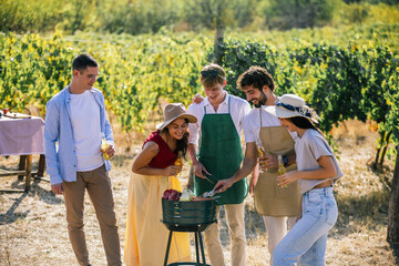 Naklejka premium Friends gathering around an outdoor grill while preparing food in a vineyard