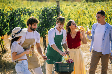 Fototapeta premium Friends preparing food and enjoying drinks together in the vineyard