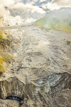 Aerial top view Georgia Svaneti Shkhara glacier summer morning with clouds drift across rugged peaks, moraine rocks foreground .Smoky mountains concept