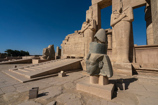 Granite head of Ramesses II in front of statues of Osiris, Ramesseum, memorial temple of Pharaoh Ramesses II, Luxor, Egypt