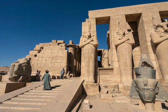Granite head of Ramesses II in front of statues of Osiris, Ramesseum, memorial temple of Pharaoh Ramesses II, Luxor, Egypt