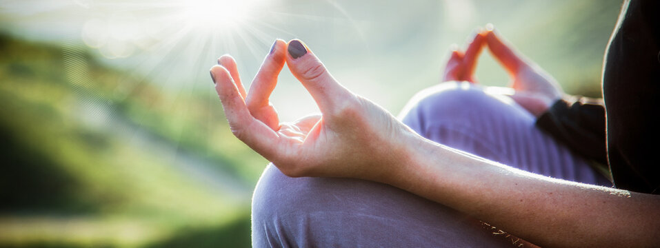 Woman doing yoga in beautiful nature background at sunset, United Kingdom