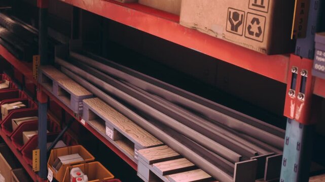 Rows of steel beams and assorted boxes fill the shelves of a busy warehouse. The setting exudes a sense of organized industry, showcasing construction supplies ready for use.