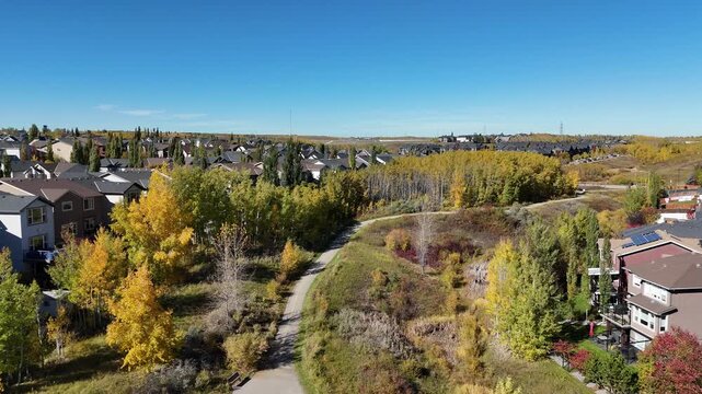 Aerial view of suburban houses in autumn along colourful ravines. 