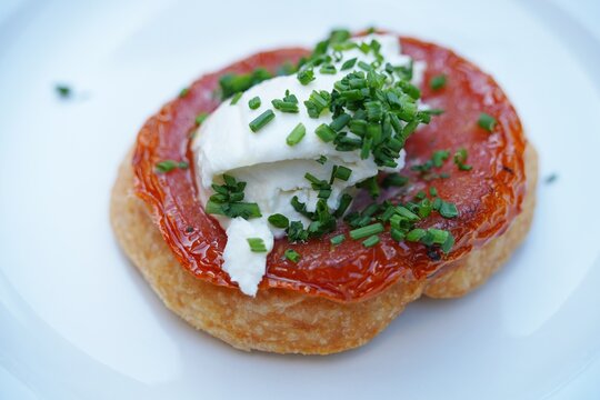 View of a tomato tarte Tatin upside down pie with cheese and chives