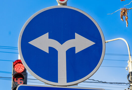 Traffic sign indicating two directions to split ahead with a clear blue sky in the background