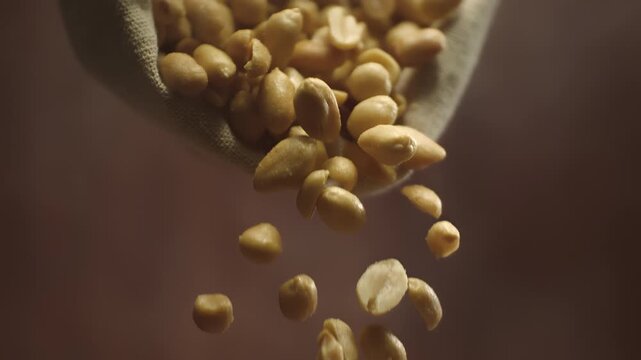 Roasted salted peanuts falling in super slow motion. Crispy snack and tasty nut close up
