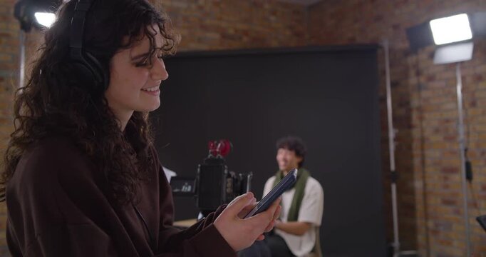 Female crew member wearing headset, reading tablet cues, directing camera in studio interview