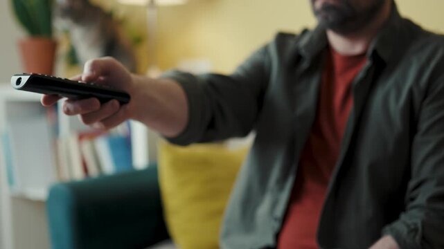Close-up of man holding television remote controller pointing at screen close shot