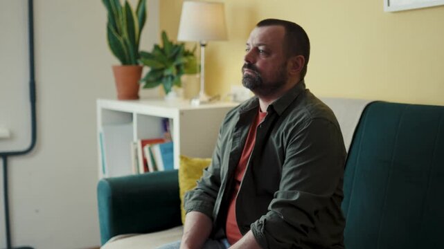 Man sitting on couch browsing media streaming service with remote controller