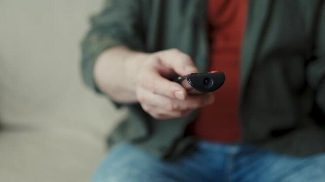 Extreme close-up of smart TV remote control being pressed by casual man