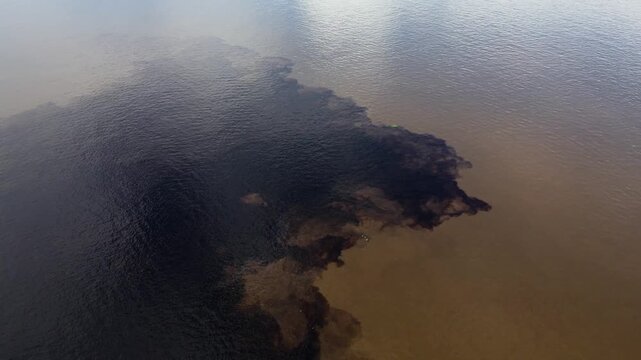 Aerial view of the confluence of the dark Rio Negro and the sandy Rio Solimoes near Manaus, Amazonas, Brazil.