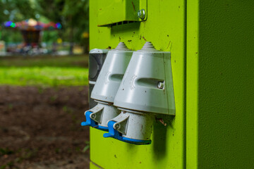 Bright Green Electrical Outlet Box at a Park Playground With Two Sockets for Connecting Devices and Equipment During a Sunny Day © Роман Булатов