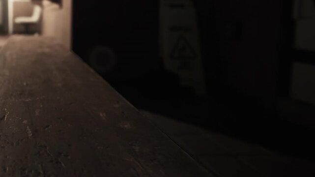 A dimly lit hallway creates an eerie atmosphere. Shadows linger along the wooden railing, revealing a sense of solitude. A faint glow beckons in the distance, hinting at untold stories.